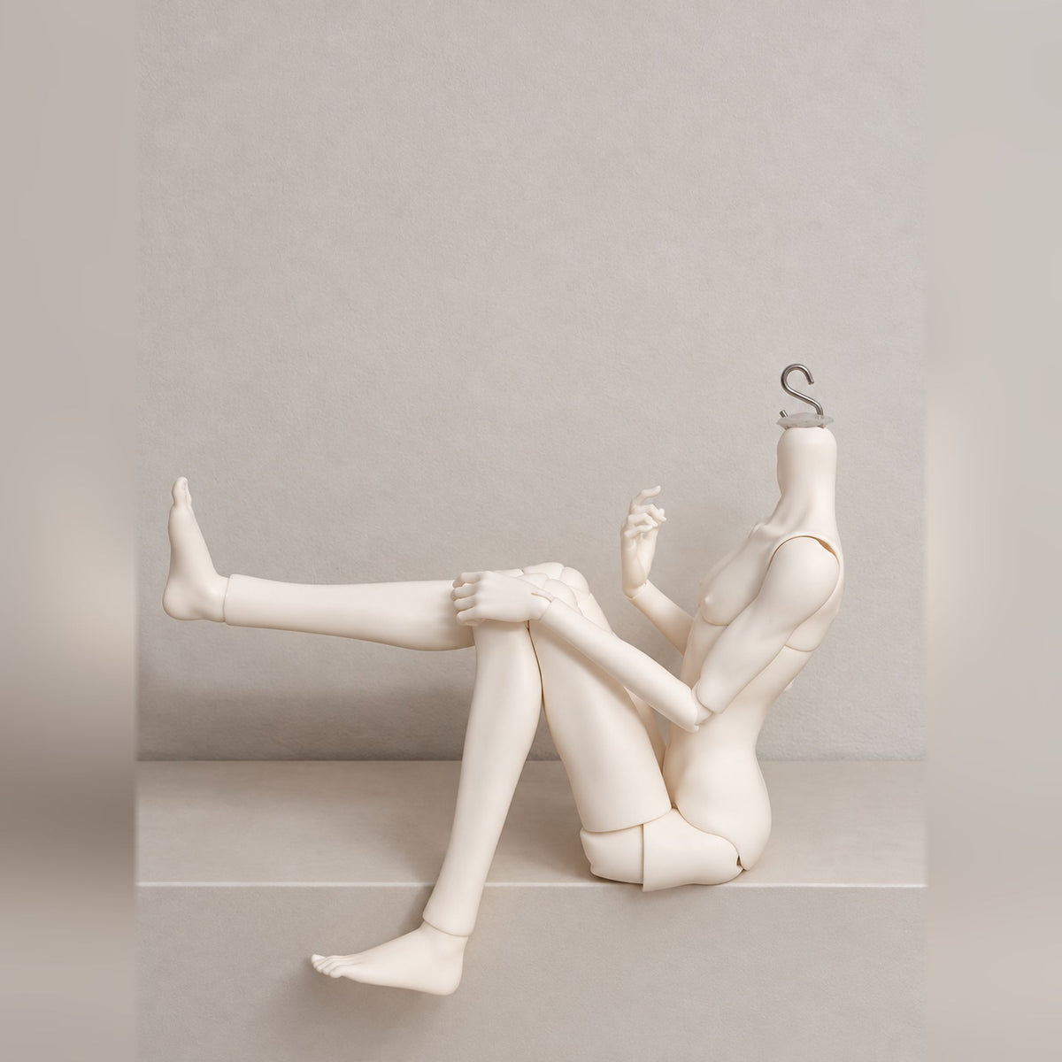 Poseable male BJD body with flexible hip and knee joints in a seated leg-lift pose