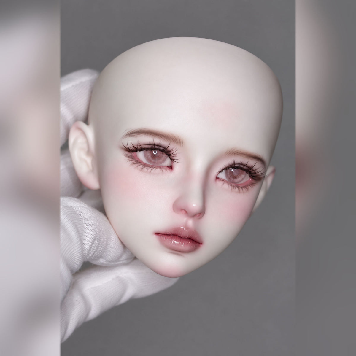 Three-quarter view of a female BJD head featuring soft blush, dramatic lashes and gently parted glossy lips