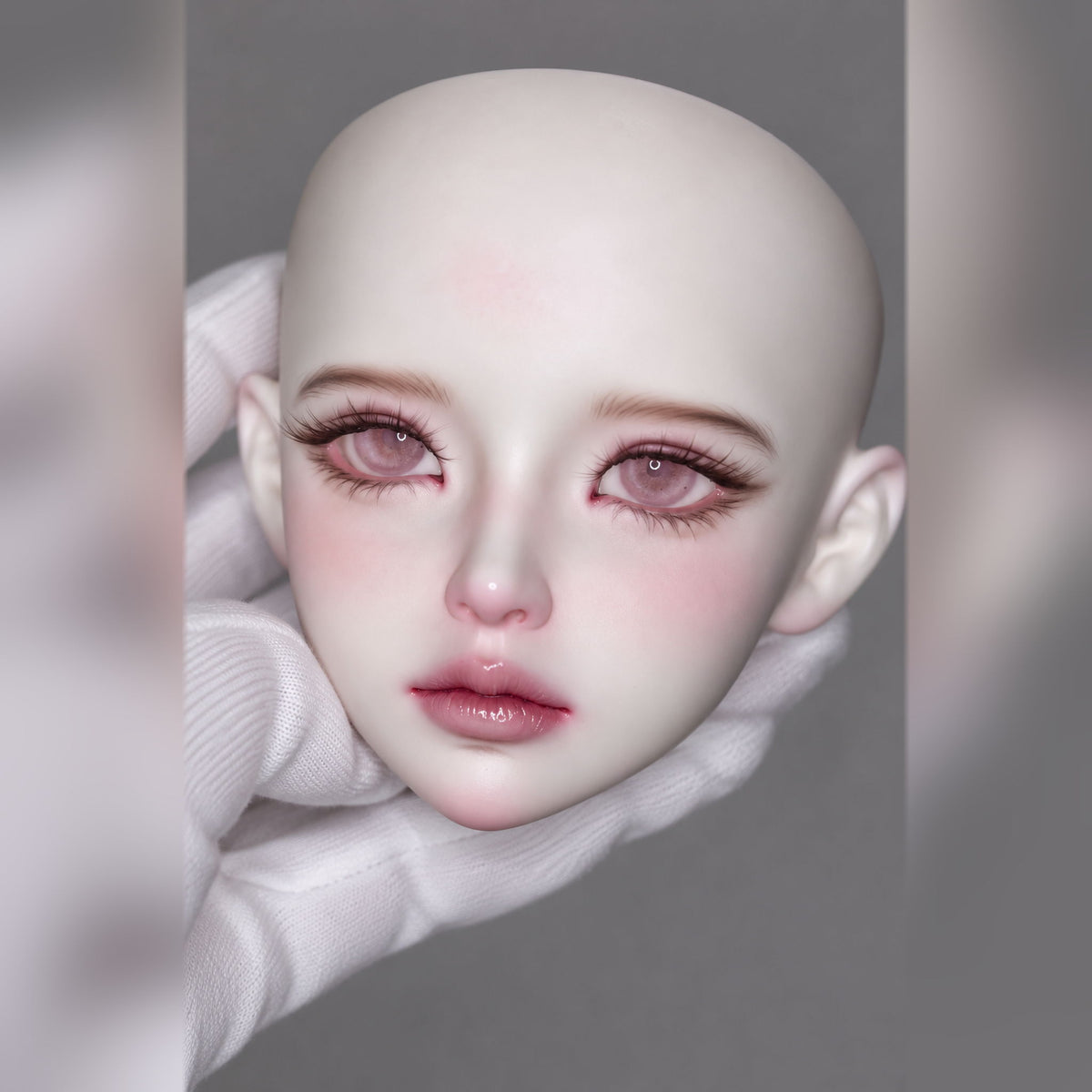 Angled close-up of a pale female BJD head with pink eye makeup, subtle shading and full glossy lips