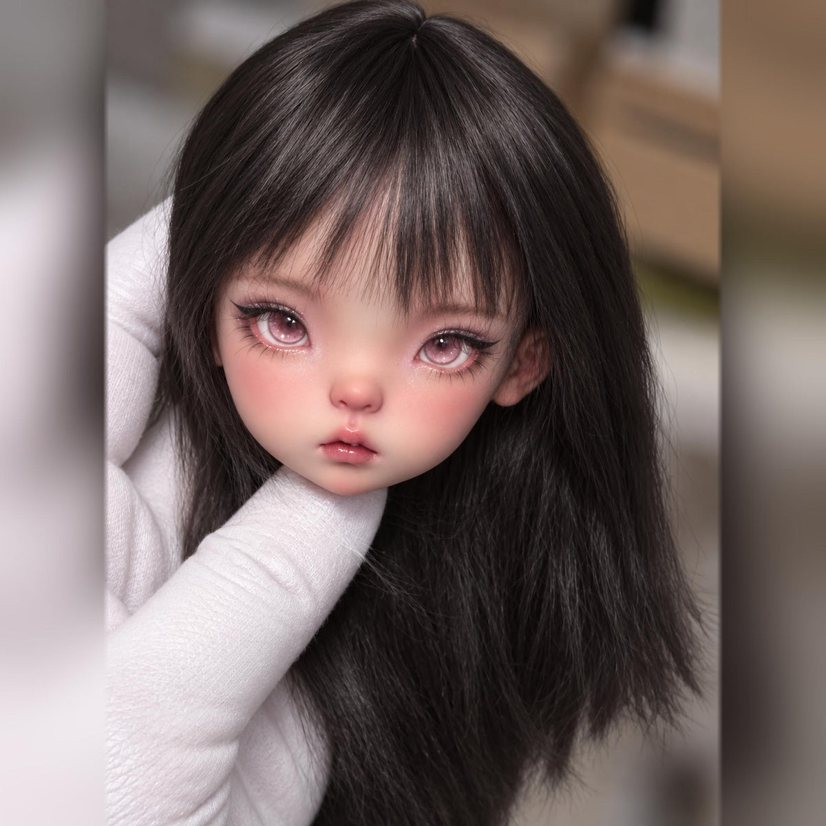 Childlike resin BJD head with long dark hair, soft pink eyes, wispy bangs and glossy parted lips