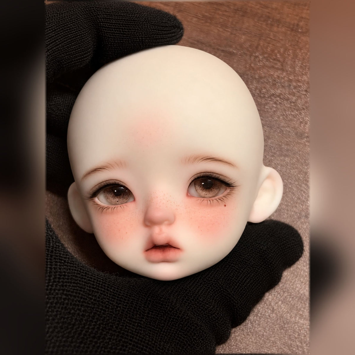 Girl BJD head with warm brown eyes, natural freckles, blush and a beauty mark