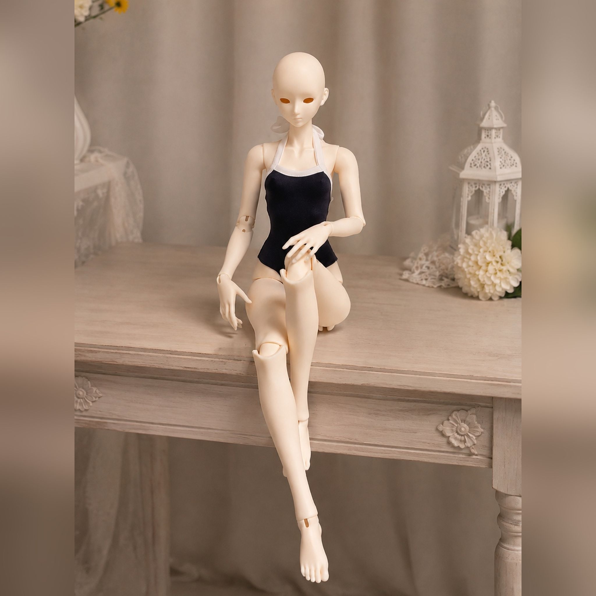 Female BJD doll body seated on a tabletop demonstrating natural sitting pose and joint flexibility